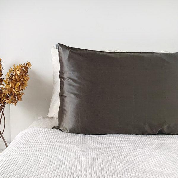 Charcoal silk pillowcase by Monday Silks NZ on a white bed, made from pure mulberry silk for anti bed hair and skin hydration benefits.