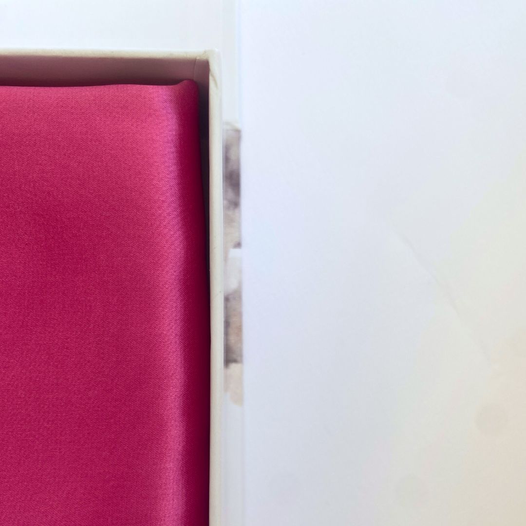 Folded fuchsia silk pillowcase in packaging from Monday Silks NZ, highlighting premium 22 momme mulberry silk quality.